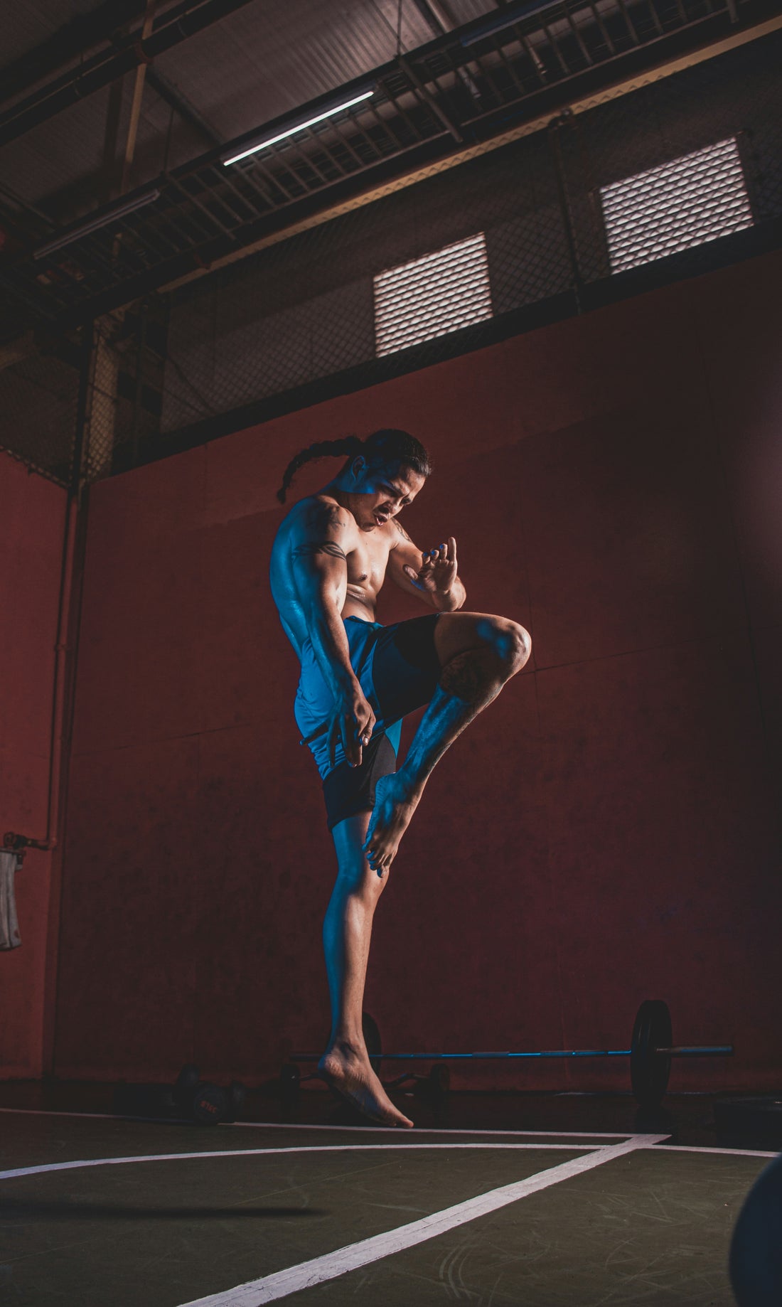 Traditional Muay Thai Gear and Outfit, Man wearing muay thai shorts and headgear in a typical muay thai knee position